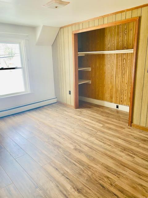 additional living space with light wood-type flooring and baseboard heating