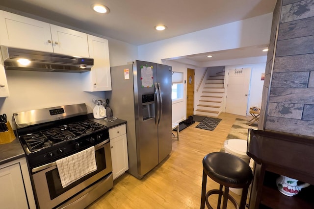 kitchen with stainless steel appliances, white cabinets, and light hardwood / wood-style flooring