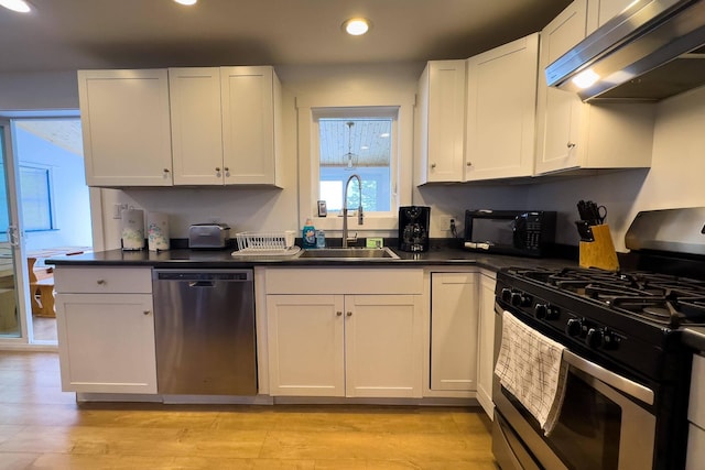 kitchen with light wood-type flooring, stainless steel dishwasher, gas range oven, ventilation hood, and sink