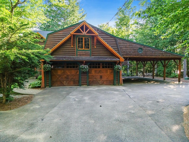 exterior space featuring a garage, driveway, log veneer siding, an outdoor structure, and a carport