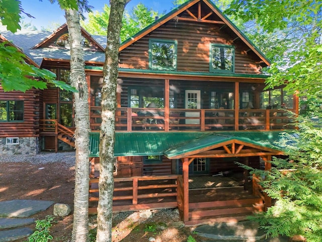 rear view of property featuring a sunroom, log exterior, and a wooden deck