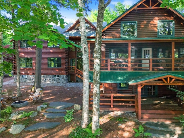 rear view of property with log siding and a sunroom