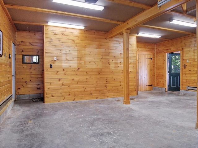 empty room featuring a baseboard heating unit, concrete floors, and wooden walls