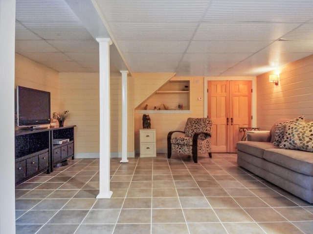 living room featuring wooden walls and tile patterned floors
