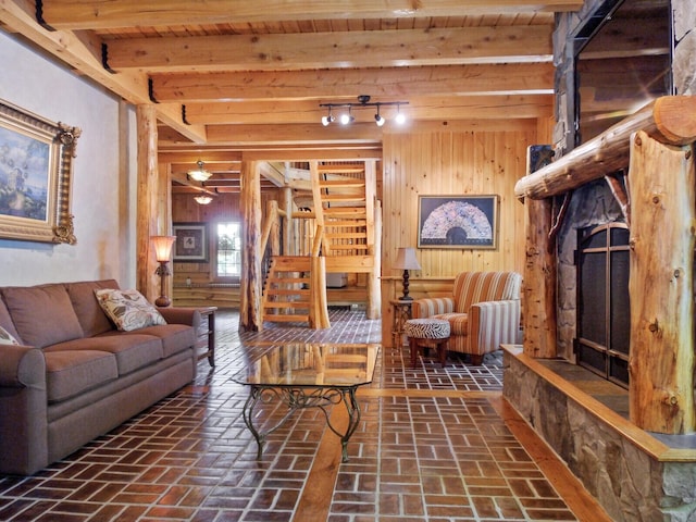 living room featuring stairs, wood walls, brick floor, and beam ceiling
