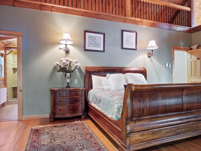 bedroom featuring radiator, wood finished floors, and baseboards
