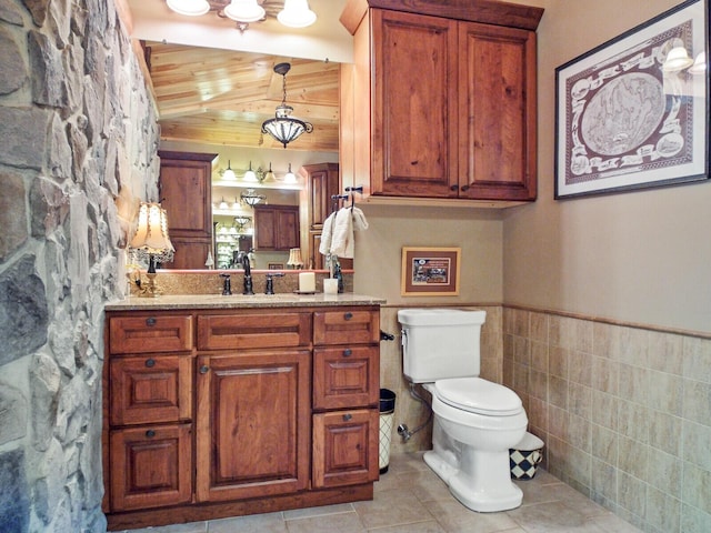 bathroom with wainscoting, toilet, wooden ceiling, tile patterned flooring, and vanity