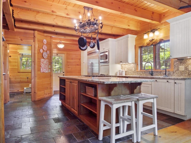 kitchen featuring built in appliances, open shelves, wood walls, and a center island
