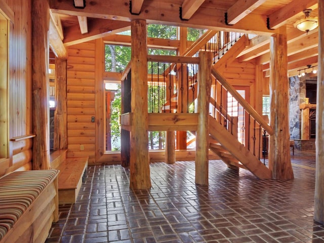 entrance foyer featuring brick floor, a wealth of natural light, and beamed ceiling
