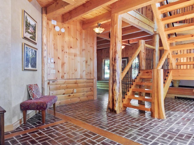 stairs featuring wood walls, brick floor, and beamed ceiling