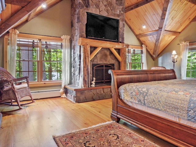 bedroom featuring lofted ceiling with beams, baseboard heating, a fireplace, and hardwood / wood-style flooring
