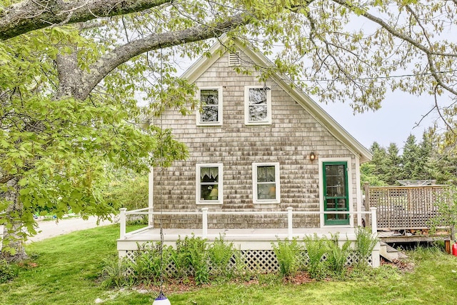 rear view of house featuring a wooden deck and a lawn