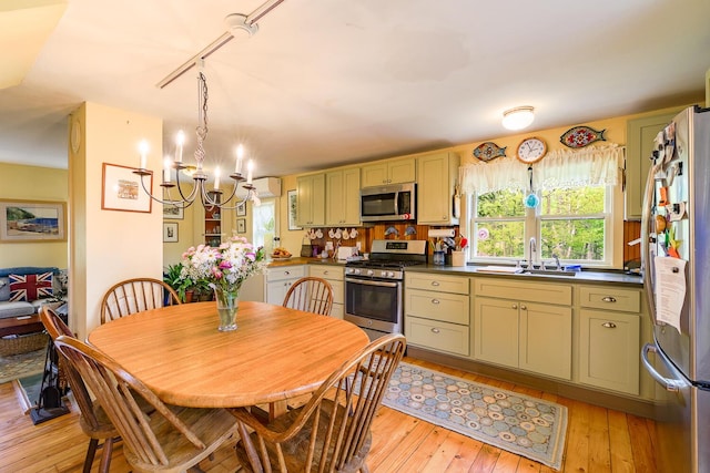 kitchen featuring sink, appliances with stainless steel finishes, a notable chandelier, green cabinetry, and light wood-type flooring