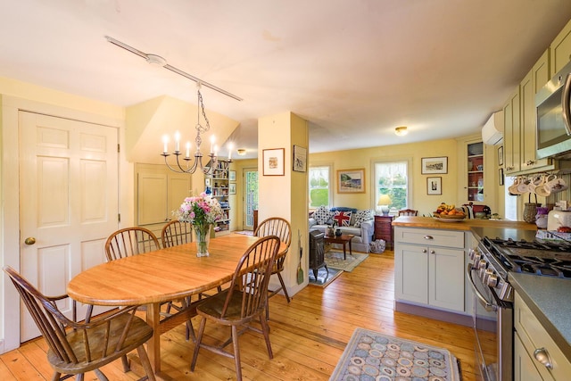 dining area featuring an AC wall unit, an inviting chandelier, and light hardwood / wood-style floors