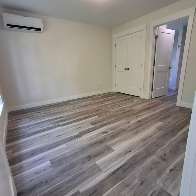 5 Apex Dr Unit 1, Westbrook, ME 04092 - unfurnished bedroom with a wall mounted air conditioner, baseboards, wood finished floors, and a closet