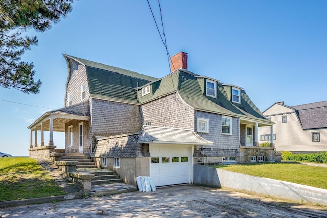 view of front of property featuring a garage, a front lawn, and a porch