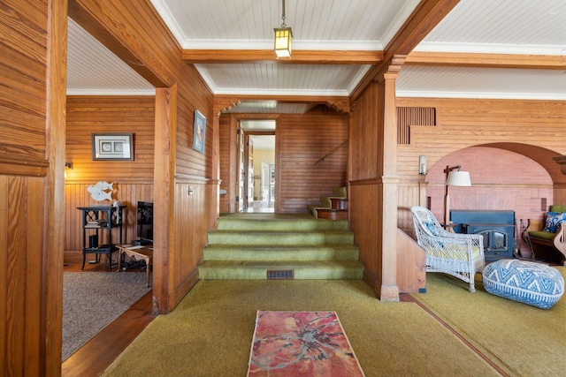 93 Beach Ave, Kennebunk, ME 04043 - entryway featuring wood walls, stairs, a wood stove, ornamental molding, and carpet flooring