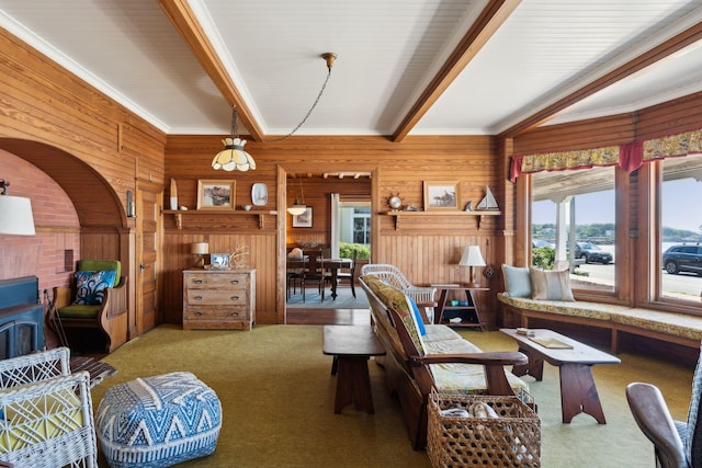 carpeted living room with beam ceiling and wood walls