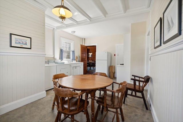 dining space featuring sink, beam ceiling, carpet, washer and dryer, and wood walls