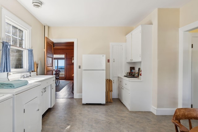 93 Beach Ave, Kennebunk, ME 04043 - kitchen featuring freestanding refrigerator, washer and clothes dryer, light countertops, and white cabinetry