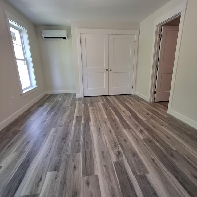7 Apex Dr Unit 2, Westbrook, ME 04092 - unfurnished bedroom featuring a wall mounted air conditioner, wood finished floors, baseboards, and a closet