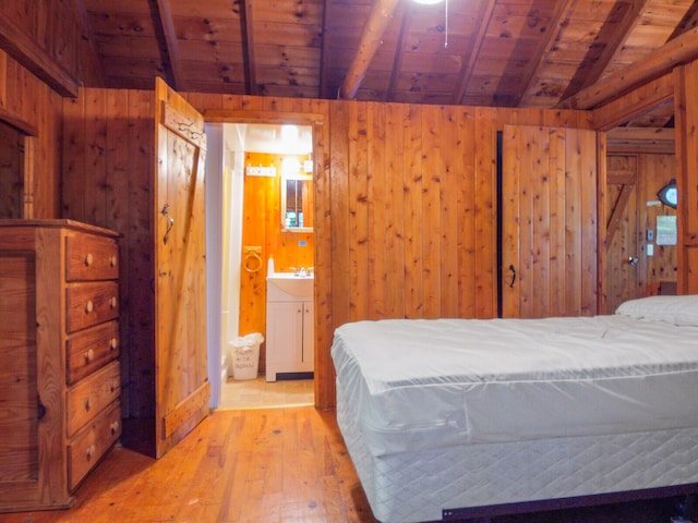 bedroom with light hardwood / wood-style floors, vaulted ceiling with beams, ensuite bath, wood walls, and wood ceiling