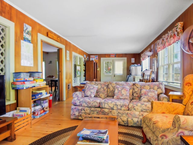 living room with wood walls, ornamental molding, and hardwood / wood-style floors