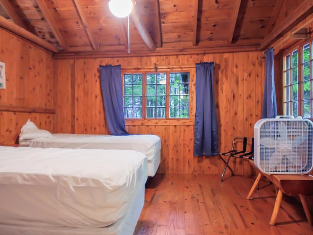 bedroom featuring wood walls, lofted ceiling with beams, wood-type flooring, and wooden ceiling