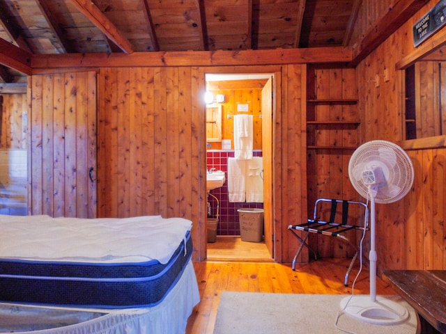 bedroom featuring light wood-type flooring, wooden ceiling, wooden walls, and vaulted ceiling with beams