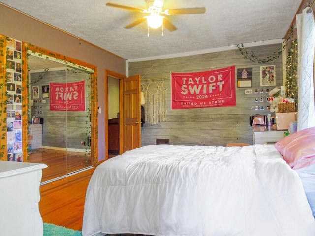 bedroom with hardwood / wood-style floors, ceiling fan, and a textured ceiling