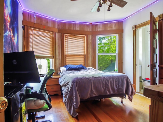 bedroom with hardwood / wood-style floors, ensuite bathroom, and ceiling fan