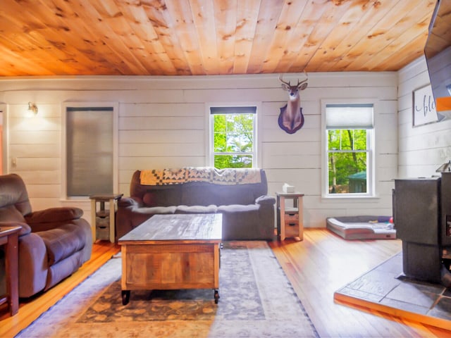 living room featuring wooden walls, hardwood / wood-style floors, wood ceiling, and a wood stove