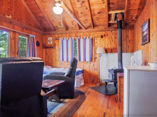 bedroom with wooden ceiling, wooden walls, vaulted ceiling with beams, and a wood stove