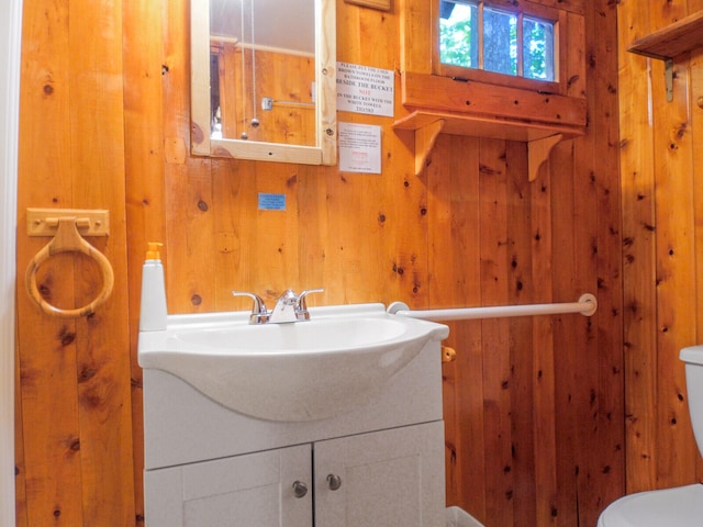 bathroom with wooden walls, vanity, and toilet