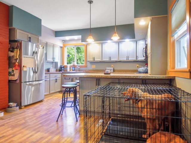 kitchen with light hardwood / wood-style floors, decorative light fixtures, a breakfast bar, white cabinets, and appliances with stainless steel finishes