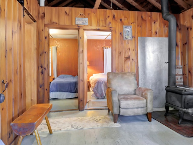 bedroom featuring wooden walls, lofted ceiling with beams, and a wood stove