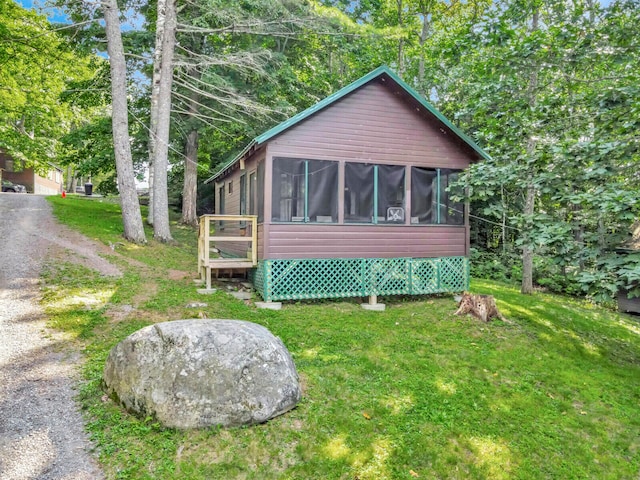 back of property featuring a sunroom and a lawn