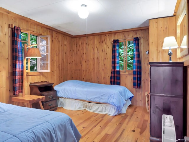 bedroom with radiator heating unit, wood walls, and hardwood / wood-style flooring