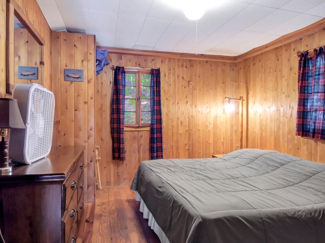 bedroom with hardwood / wood-style floors and wooden walls