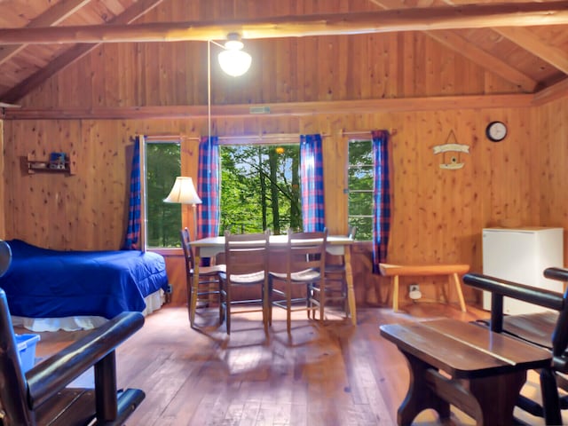 bedroom with wooden walls, beam ceiling, wooden ceiling, and wood-type flooring