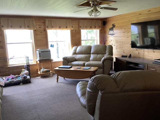 carpeted living room featuring wood walls, cooling unit, and ceiling fan