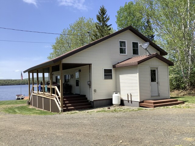 rear view of property featuring covered porch and a water view