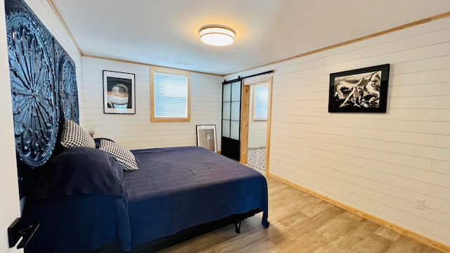 bedroom featuring crown molding, a barn door, and hardwood / wood-style floors