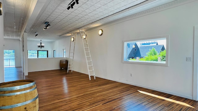 interior space featuring hardwood / wood-style flooring, track lighting, and a notable chandelier