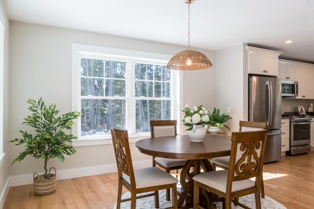 dining area featuring light wood-style flooring, plenty of natural light, and baseboards