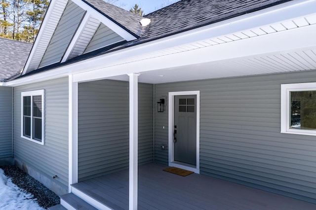 view of exterior entry featuring a shingled roof