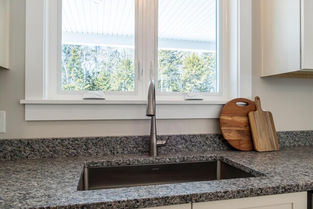 room details featuring white cabinetry, dark countertops, and a sink