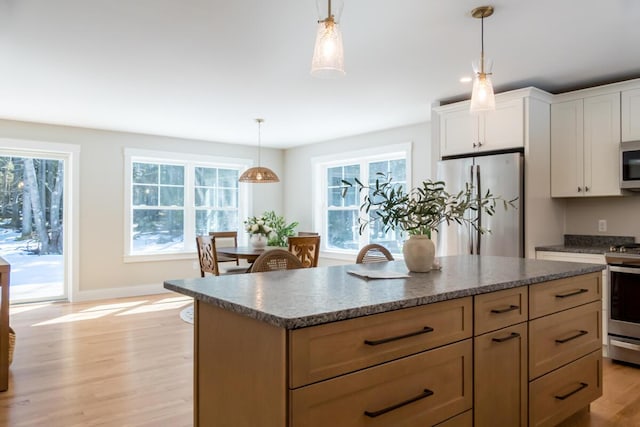 kitchen featuring light wood finished floors, plenty of natural light, appliances with stainless steel finishes, and a kitchen island