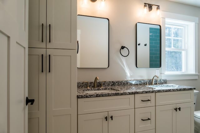 bathroom featuring double vanity, toilet, and a sink