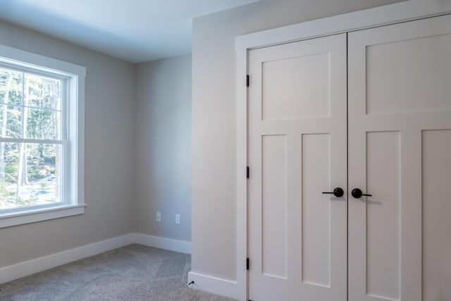 unfurnished bedroom with baseboards, multiple windows, and carpet floors